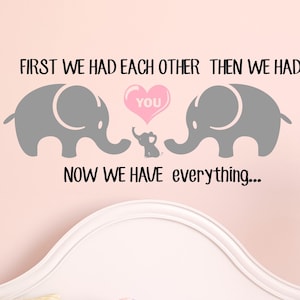 Pu&ograve; includere: Un adesivo da parete per l'asilo con due elefanti grigi e un elefante pi&ugrave; piccolo al centro. L'adesivo recita "First we had each other then we had you. Now we have everything..."