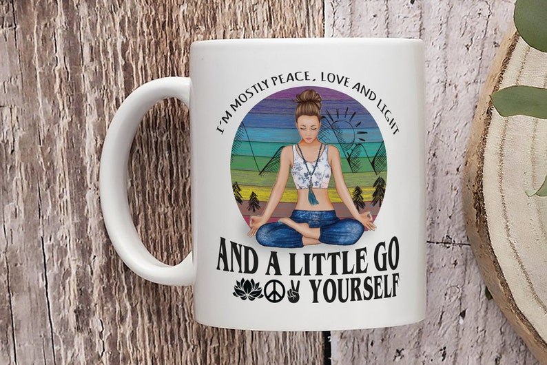 May include: White ceramic mug with a colorful illustration of a woman meditating in a forest setting. The text reads "I'm mostly peace, love and light and a little go yourself" with a peace sign and a lotus flower.