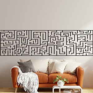 May include: A large, black maze design mounted on a white wall above a brown leather sofa. The maze is a complex pattern of lines, creating a challenging puzzle. The room has an orange and white color scheme, with decorative plants and pillows.
