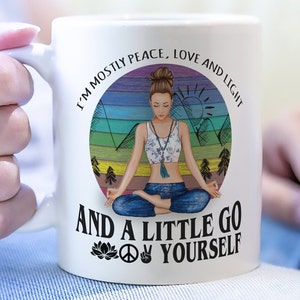 May include: White ceramic mug with a colorful illustration of a woman meditating in front of a mountain range. The text reads "I'm mostly peace, love and light and a little go yourself" with a peace sign and a lotus flower.