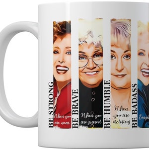Może przedstawiać: Biały ceramiczny kubek do kawy z czterema kolorowymi portretami kobiet i inspirującym tekstem. Tekst brzmi: "Bądź silny", "Bądź odważny", "Bądź pokorny" i "Bądź twardzielem".