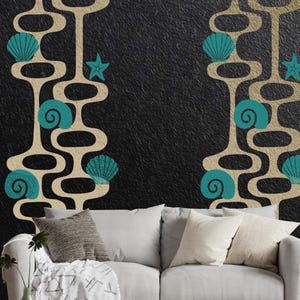 May include: Wall art featuring a mid-century modern design with beige, teal, and black elements. The design includes stylized seashells and starfish. The artwork is displayed above a white sofa with decorative pillows, creating a coastal theme.