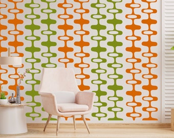 May include: A white chair with a light pink cushion sits in front of a wall with a repeating pattern of orange and green abstract shapes.