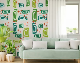 May include: A light green sofa with white pillows in front of a wall with a retro pattern of green and orange swirls and stars.