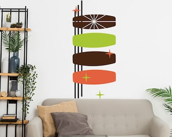 Puede incluir: Una calcomanía de pared moderna de mediados de siglo con cinco formas abstractas en marrón, naranja, verde y blanco. Las formas están dispuestas verticalmente y están acentuadas con pequeñas estrellas.