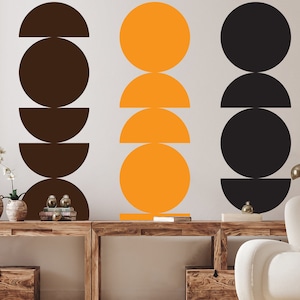 Peut inclure: Trois ensembles d'autocollants muraux géométriques en noir, marron et orange. Chaque ensemble comprend un cercle, un demi-cercle et un cercle plein.