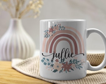May include: White ceramic mug with a pink and brown rainbow design, floral accents, and the name "Julie" in black script.
