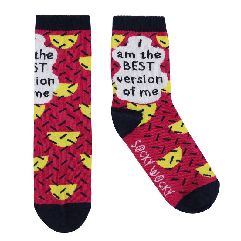 May include: A pair of pink and yellow socks with a white speech bubble that says "I am the BEST version of me". The socks have a navy blue cuff and toe.