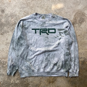 May include: A gray long-sleeve sweatshirt with a tie-dye effect. The word "TRD" is printed in dark green across the chest. The sweatshirt has a crew neck and ribbed cuffs and hem.