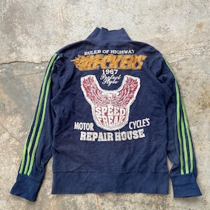 Puede incluir: Chaqueta azul marino con cremallera y rayas verdes en las mangas. La parte trasera presenta un gráfico con el texto "Ruler of Highway RECKERS 1967 Perfect Style" y "SPEED FREAK CYCLE'S MOTOR REPAIR HOUSE".