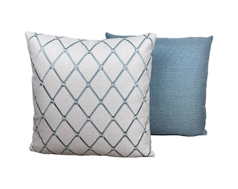 May include: Two decorative throw pillows, one with a white background and a blue diamond pattern, and the other a solid blue.