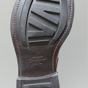 May include: Close-up of the brown leather sole of a shoe with a Goodyear Welted label and the text "Made in England".