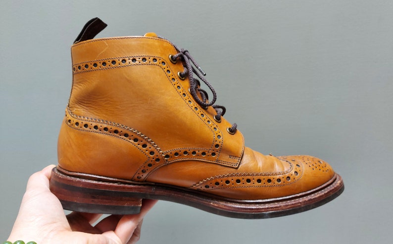 May include: A brown leather brogue boot with a lace-up closure and a decorative wingtip design.