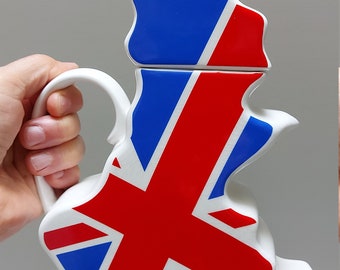 May include: A white ceramic teapot shaped like the United Kingdom with a Union Jack design. The teapot has a handle and a lid.