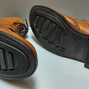 May include: A pair of brown leather brogue boots with a black rubber sole. The sole has the text "Genuine Goodyear Welt" printed on it.