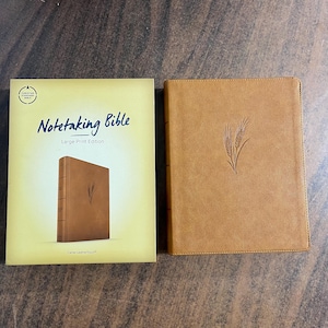 May include: A tan "Notetaking Bible" with a large print edition cover and a matching Bible. The cover features a wheat stalk design. The book is "Camel LeatherTouch".
