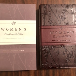 May include: A burgundy leather-bound devotional Bible with a floral design and the text "Women's Devotional Bible, English Standard Version" on the cover.