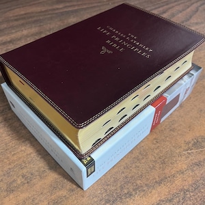 May include: A burgundy leather-bound Bible with gold lettering and a gold-edged page. The title reads "The Charles F. Stanley Life Principles Bible".