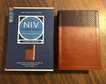 Op de afbeelding: Een bruine leren New International Version (NIV) Study Bible met de woorden "NIV Study Bible" en "Fully Revised Edition" gedrukt op de voorkant. De omslag heeft ook een groot lettertype ontwerp en de woorden "Large Print" gedrukt op de voorkant.