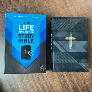 May include: A black and blue study Bible with the title "Boys Life Application Study Bible" and the words "Neon & Black Edition" and "NLT" on the cover. The Bible has a glow-in-the-dark cover.