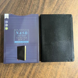 May include: A black leather-bound New American Standard Bible with the text "NASB 1995 Text Thinline Bible Large Print Standard Bible" on the cover.
