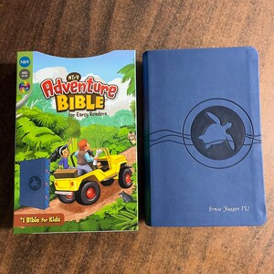 May include: A blue hardcover book with the title "Adventure Bible for Early Readers" in white text. The book cover features a turtle illustration and the text "Ernie Yeager 1/U".