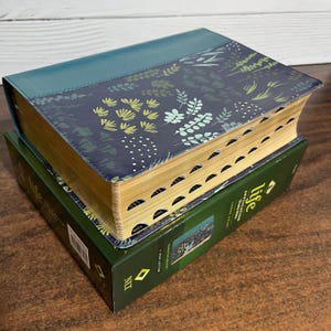May include: A teal and navy blue hardcover book with a floral pattern. The book is titled "Life" and is in a green box.