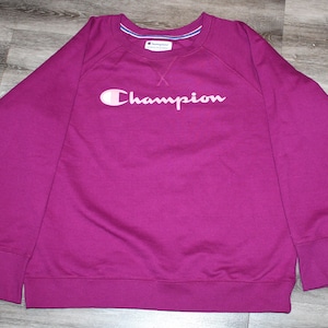 May include: A magenta sweatshirt with a white Champion logo.