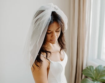 Velo de novia minimalista de una sola capa con hombros suaves y borde sin rematar, 50 cm de largo. Disponible en blanco, marfil, marfil claro y negro.