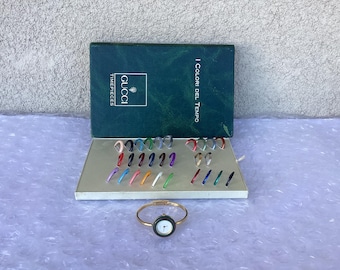 May include: A Gucci Timepieces set featuring a gold-tone watch with a black face and a variety of interchangeable colored bezels. The set includes a box with the Gucci logo and the text "I Colori Del Tempo".