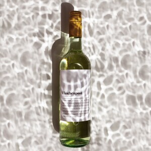 May include: A clear glass bottle of white wine with a white label that says "Flaschenpost" in black text. The bottle is sitting on a white surface with a pattern of light and dark areas.