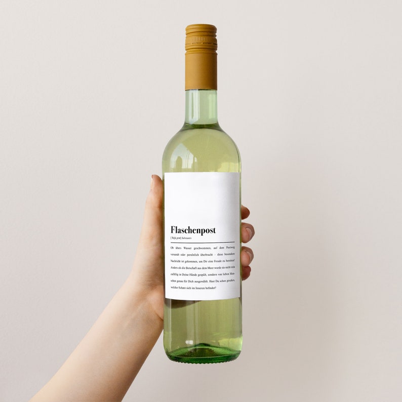 May include: A green glass bottle of white wine with a white label that says "Flaschenpost" and a description of the wine in German. The bottle is being held by a hand.