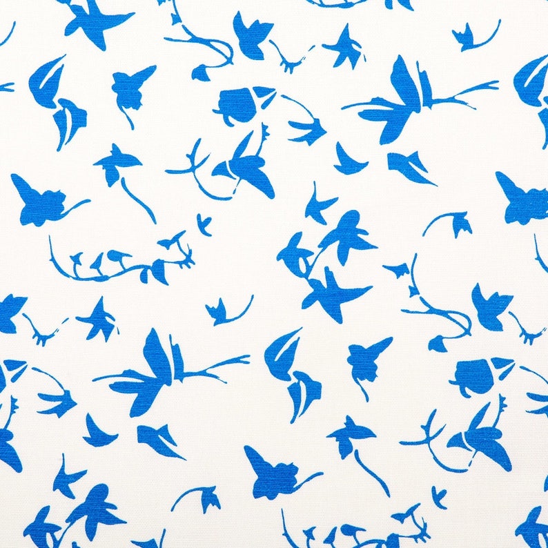 May include: A white fabric featuring a repeating pattern of scattered, vibrant blue abstract floral and leaf shapes. The design consists of various organic silhouettes, including small sprigs, individual petals, and leafy stems, all printed in a solid, bold blue color against a clean, plain white background.
