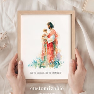 Puede incluir: Una impresión enmarcada de estilo acuarela que muestra una figura con halo sosteniendo a un niño pequeño, de pie en un campo de flores azules. La impresión incluye el texto FOREVER CHERISHED, FOREVER REMEMBERED. El marco es de madera clara.