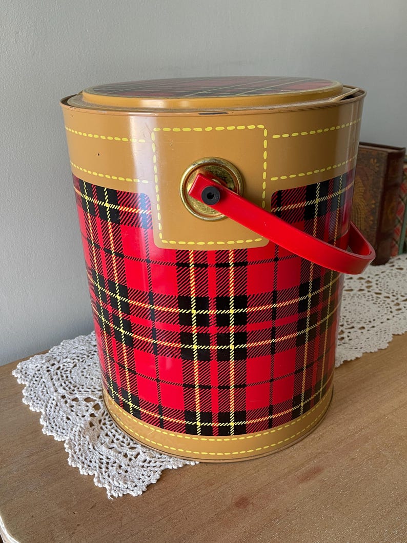 Peut inclure: Une glaci&egrave;re en m&eacute;tal rouge, noir et jaune &agrave; carreaux avec une garniture en simili cuir marron et une poign&eacute;e rouge.