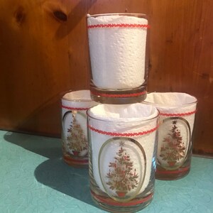 May include: Set of four vintage Christmas glasses with gold and red trim. Each glass features a gold Christmas tree design with red and green accents.