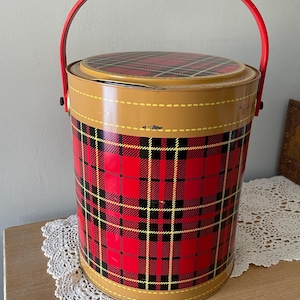 Peut inclure: Une glaci&egrave;re en m&eacute;tal rouge et noir &agrave; carreaux avec une poign&eacute;e rouge. La glaci&egrave;re est orn&eacute;e d'une bordure jaune autour du haut et du bas.