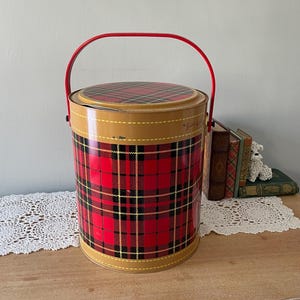 Peut inclure: Glaci&egrave;re en m&eacute;tal rouge et noir &agrave; carreaux avec une poign&eacute;e rouge. La glaci&egrave;re a une bordure jaune et le texte "The Scotch Kilt" est visible sur le c&ocirc;t&eacute;.