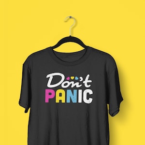 Puede incluir: Camiseta negra con el texto "Don't Panic" en blanco con corazones coloridos sobre el texto.