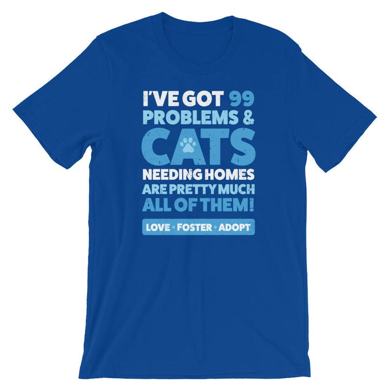 Puede incluir: Camiseta azul con un gr&aacute;fico blanco que dice "Tengo 99 problemas & gatos que necesitan hogar, son casi todos! Amar, acoger, adoptar"