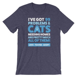 Puede incluir: Una camiseta azul marino con un gr&aacute;fico blanco desgastado que dice "Tengo 99 problemas & GATOS que necesitan hogar, casi todos! Amar, acoger, adoptar".