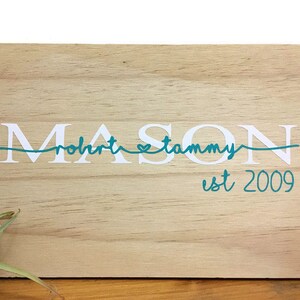 Peut inclure: Une pancarte en bois avec le texte "MASON" en lettres blanches avec un cœur turquoise et le texte "robert & tammy est 2009" en turquoise.