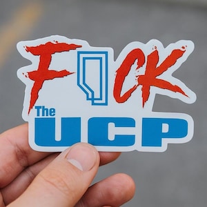 Può includere: Un adesivo bianco con le parole "F*ck The UCP" in rosso e blu. La parola "F*ck" è in un carattere stilizzato e frastagliato, e la parola "UCP" è in un carattere in grassetto e a blocchi. L'adesivo è tenuto in mano.