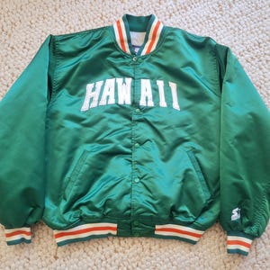 Könnte beinhalten: Grüne Satin-Bomberjacke mit weißem "HAWAII"-Schriftzug und orange-weiß gestreiftem Besatz. Die Jacke hat einen Druckknopfverschluss und ein Starter-Logo am Ärmel.