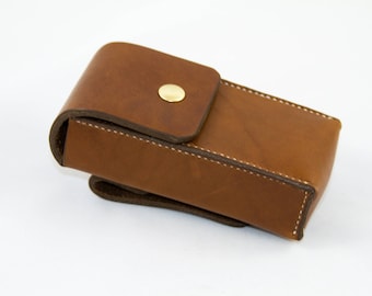 May include: A brown leather case with a brass button closure. The case is designed to hold a small item, such as a pen or a knife.