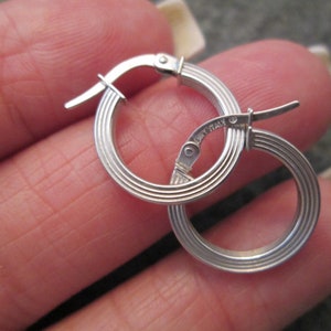 May include: Silver hoop earrings with a ridged design and a hinged clasp. The earrings are marked "Italy".