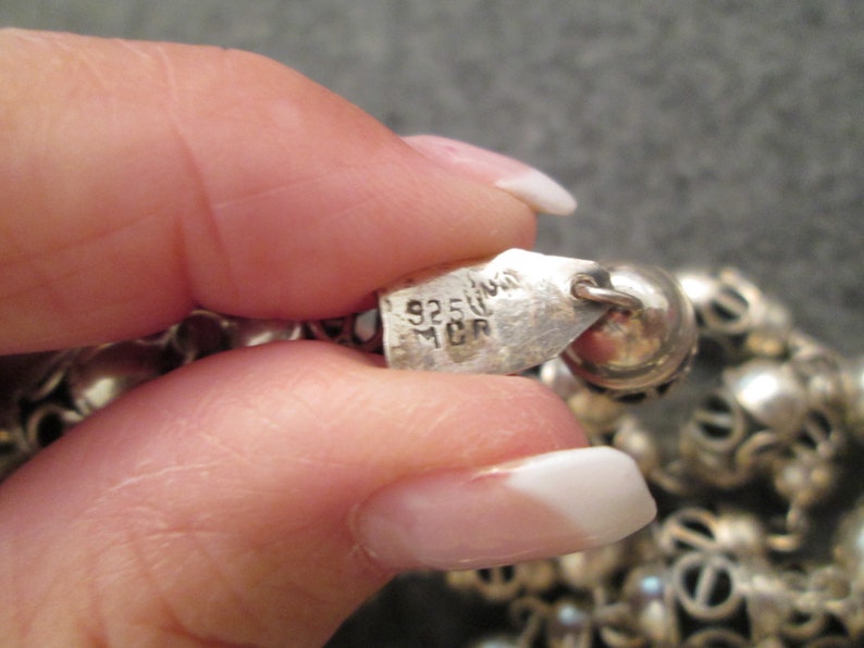 May include: A silver necklace with a silver tag that reads "925 Italy MCR".