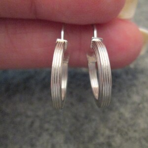 May include: A pair of silver hoop earrings with a ridged design.