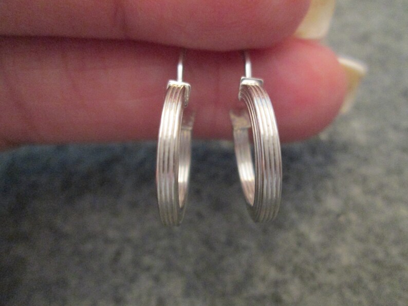 May include: A pair of silver hoop earrings with a ridged design.