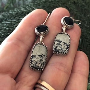 May include: Silver dangle earrings with a black gemstone and a rectangular pyrite stone.